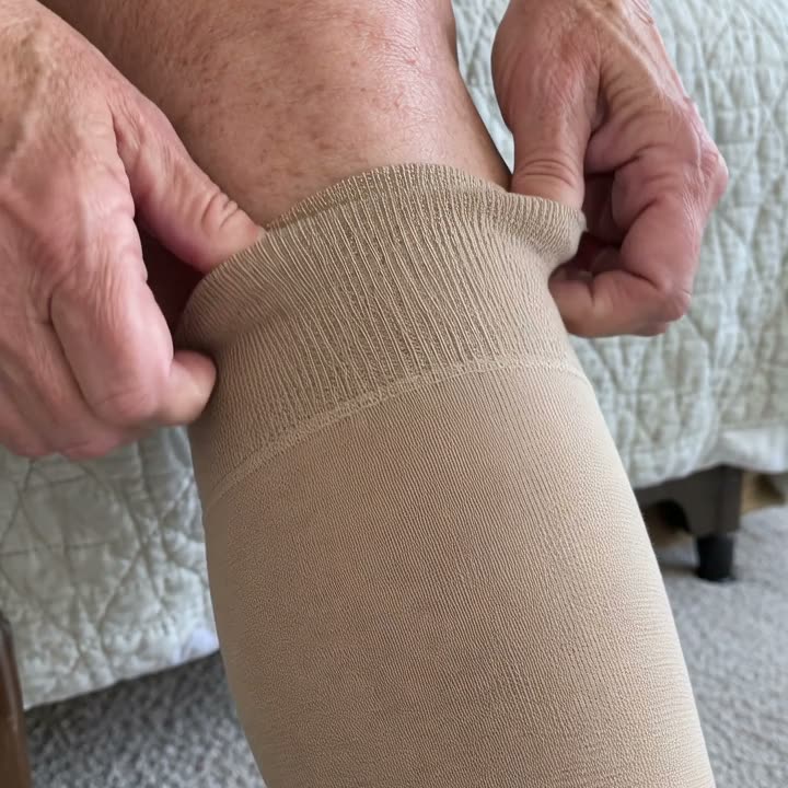 Hands pinching the tight top of a compression sock